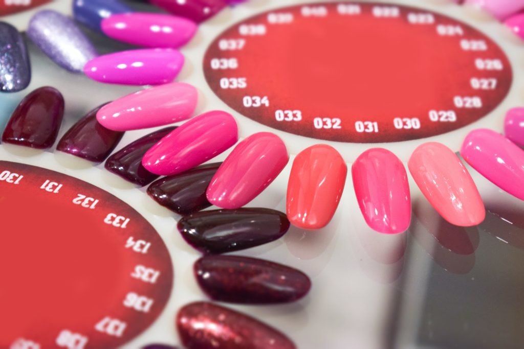 Different colorful nails polish manicure palette Background. Samples of nail varnishes. False