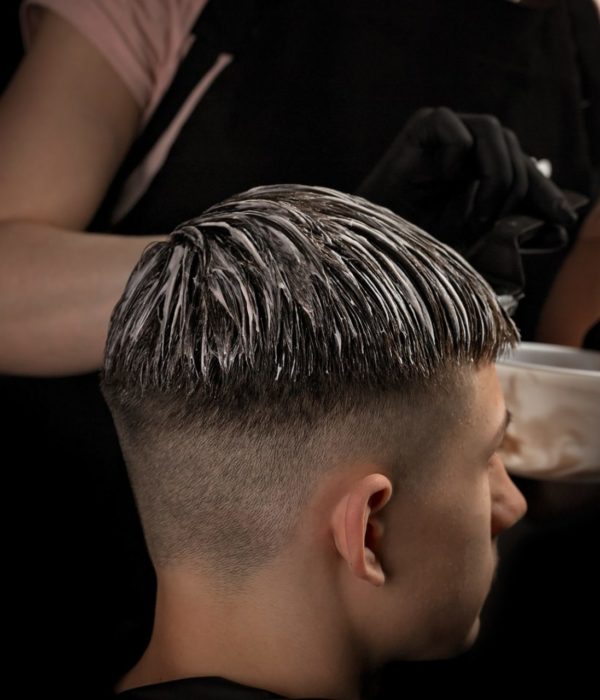 Professional hairstyle. Model and trendy hairdressed. Barber is coloring male hair.